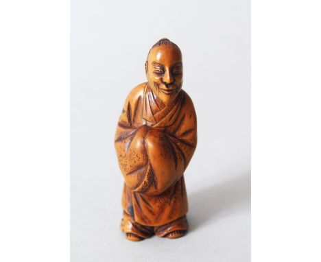 A JAPANESE MEIJI PERIOD CARVED WOODEN NETSUKE OF A CHINESE LITERATUS, stood holding his hands together but covered by volumin