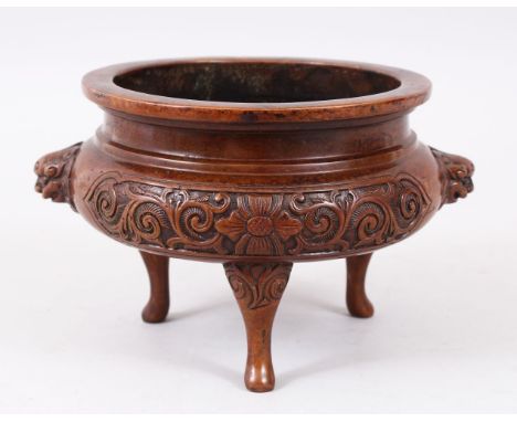 A 19TH / 20TH CENTURY CHINESE BRONZE TRIPOD CENSER, with moulded lion dog head handles, panels of floral decoration, stood on