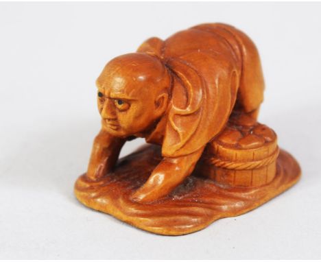 A JAPANESE MEIJI PERIOD CARVED BOXWOOD NETSUKE OF A CLAM FISHERMAN, stood knee deep in water feeling for clams, the base arti