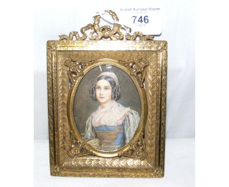 An 8cm x 6cm oval portrait miniature of a seated lady in decorative brass frame