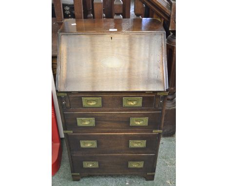 A small brass bound oak campaign bureau, fall front enclosing pigeon holes and drawer, leather inlaid writing surface, four d