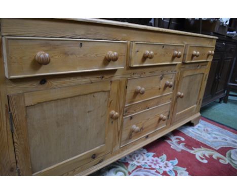 A modern pine sideboard, three short drawers over two faux drawer cupboard flanked by panelled cupboards, bracket feet.