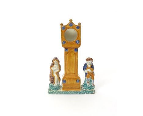 A Pratt ware watch stand  early 19th century, modelled as a longcase clock flanked by two boys emblematic of Autumn with a sh