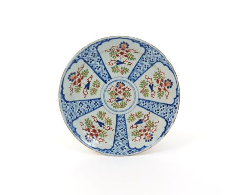 A Bristol delftware plate  c.1710, painted in blue, green and red with five petal-shaped panels of flowers and leaves, reserv