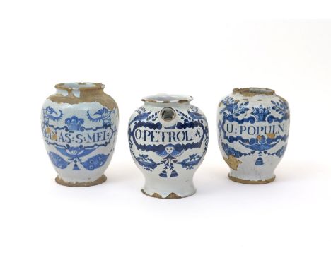 Three English delftware drug jars  18th century, two dry drug jars painted in blue, each with a cartouche surmounted by birds