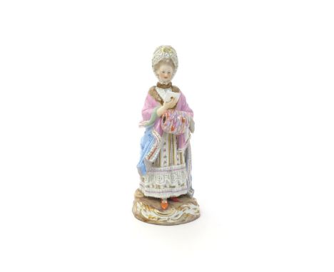 A Meissen figure of the Racegoer's Companion  19th century, wearing a fur-lined pink cloak over a striped floral dress, her l