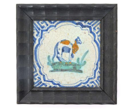 A Dutch Delft tile  17th century, painted in blue, green and ochre with a camel standing four square on grass, within a shape