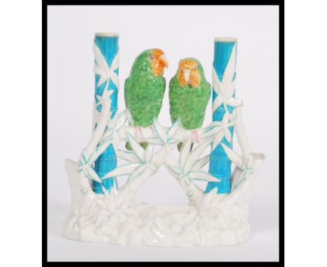 A late 19th Century Victorian Worcester Aesthetic Movement spill vase featuring a pair of parakeets in green and orange raise