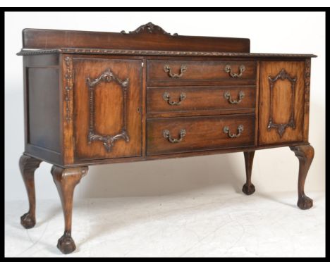 A 1930's Chippendale style mahogany sideboard credenza having a central bank of graduating drawers flanked by twin cupboards 