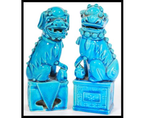 A pair of Oriental Chinese 20th Century ceramic temple lion dogs of Fu in blue raised on square pedestal bases.