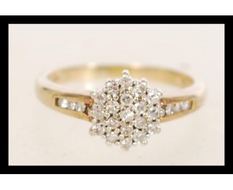 A hallmarked 9ct gold diamond cluster ring having a central flower head with diamond encrusted shoulders. Weighs 3.1 grams si