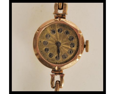 A vintage 20th Century Art Deco 9ct gold ladies wrist watch having a yellow metal face, arabic numerals to the chapter ring a