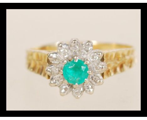 A stamped 18ct gold emerald and diamond cluster ring set with a central emerald surrounded by a diamond halo. Weight 3.8g. Si