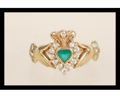 A hallmarked 9ct gold Claddagh ring set with a central green stone with white stone accents. Weight 3.1g. Size&nbsp; P.