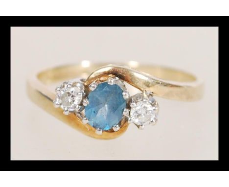 A hallmarked 9ct gold topaz and diamond ring having a crossover setting. Diamonds total approx 10pts. Weight 2.9g. Size O.