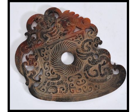 A Chinese 20th Century large carved jade roundel being brown in colour with carved and pierced decoration of dragons. Measure