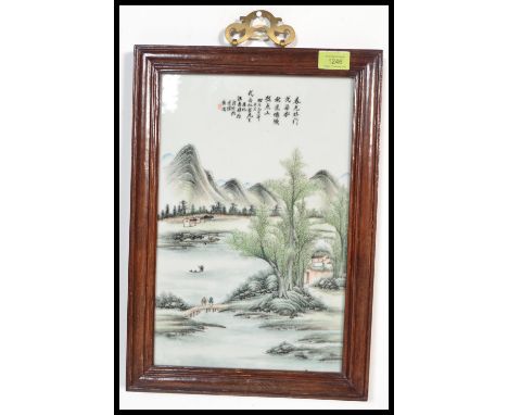 A Chinese large porcelain wall plaque being set to a wooden frame with brass lattice pierced hanging mount. The ceramic plaqu