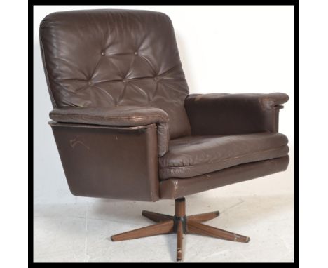 A vintage 1960's / 70's retro Danish swivel armchair upholstered with brown leather, button backed with padded arms, raised o