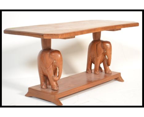 An early 20th century hardwood coffee table of rectangular form being raised on elephant carved supports with further tier be