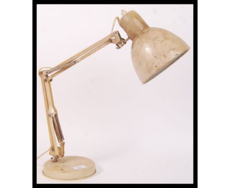 A 20th century retro vintage anglepoise desk lamp in a cream colourway being raised on a circular terraced base with adjustab