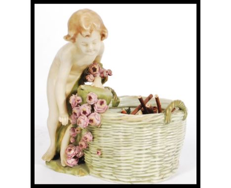 An Austrian bisque ware&nbsp; potpourri basket in the form of a cherub / child with floral basket leaning on the larger ceram