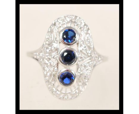 A stamped silver Art Deco style ring having an oval form central panel set with diamonds and three round sapphires. Weight 3.