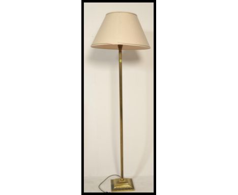 A brass Corinthian column standard lamp, with a cream lined fabric shade, on square base with paw feet.