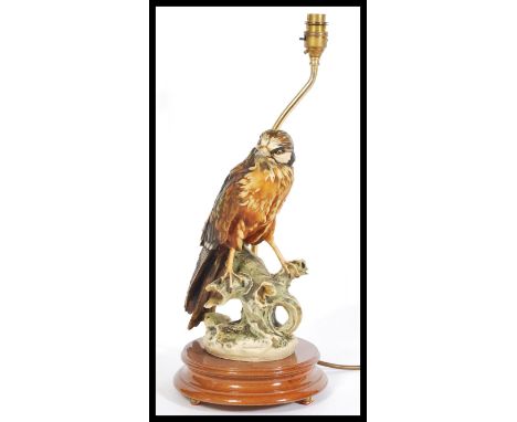 A 20th Century ceramic table lamp in the form of a bird of prey, the bird sat on a naturalistic base on wooden socle plinth b