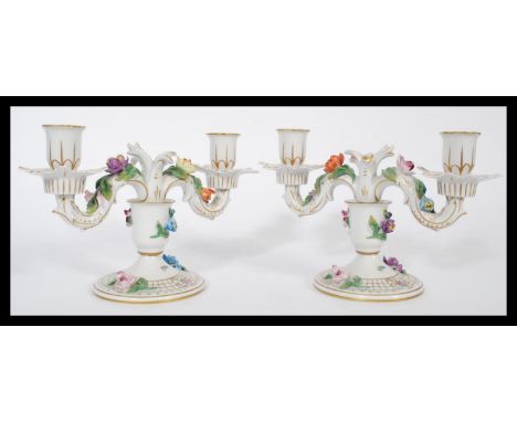 A pair of Dresden porcelain double sconce candelabras, each decorated with applied ceramic flowers and gilt motifs and raised