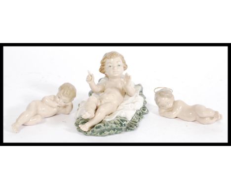 A group of three LLadro and Nao figurines to include Lladro reclined cherub with hands raised, reclined cherub with gilt meta