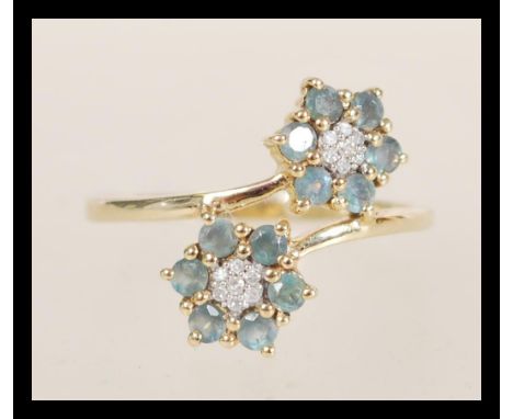 A hallmarked 10ct gold ring having a double flower head design set with white and green stones. Import hallmarks. Weight 2.1g