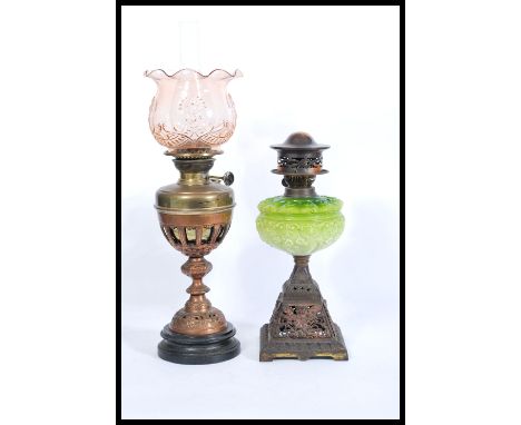Two early 20th Century oil lamps to include a brass round base example with a pink glass shade to the top and fanned rim and 