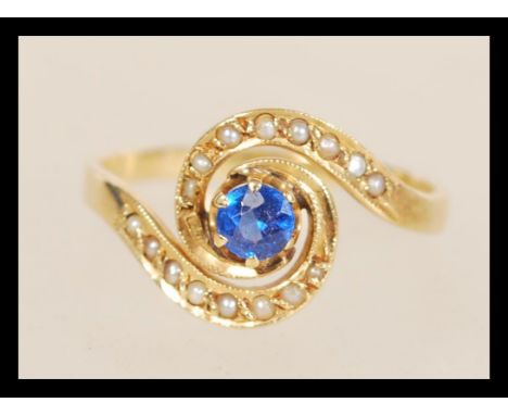 A stamped 18ct gold ring with a central prong set blue stone and seed pearl accent stones. Weight 2.3g. Size Q.&nbsp;