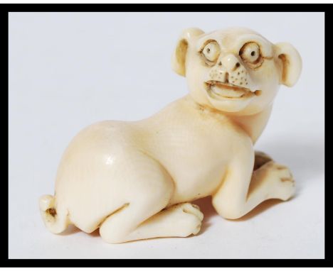 A rare Meiji period ivory Netsuke of a crouching dog with its head turned back, sat on 4 feet, indistinctly signed to the bas