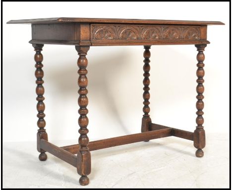 An 18th century Jacobean revival carved oak lowboy writing table desk being raised on block and turned legs with stretchers. 