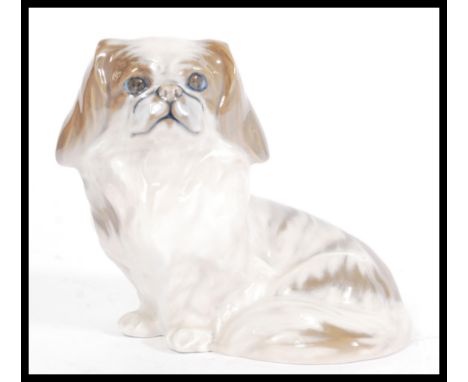 A Royal Copenhagen ceramic dog figurine of sitting Pekingese model number 1772. Painted and printed marks to base. Measures 1