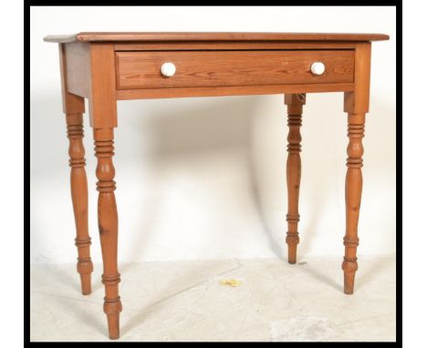 A 19th century Victorian pitch pine writing table desk being raised on turned legs with single drawer, white ceramic handles 