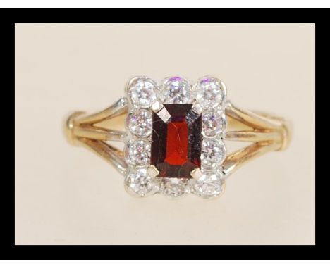 A hallmarked 9ct gold ring set with a rectangular faceted red stone with a halo of white stones. Hallmarked Birmingham. Weigh