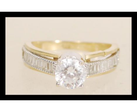 A hallmarked 9ct gold ring prong set with a brilliant cut white stone and square cut accent stones to the shoulders. Hallmark