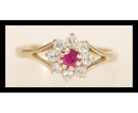 A hallmarked 9ct gold ruby and diamond ring set with a central ruby surrounded by a halo of diamonds having split shoulders. 