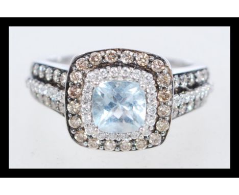 A hallmarked 14ct white gold, diamond and aquamarine ring, branded Le Vian, set with a cushion cut aquamarine surrounded by a