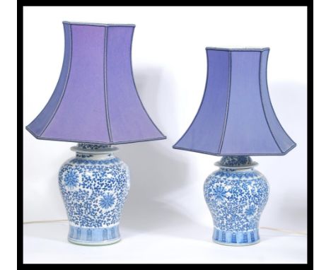 A pair of Chinese blue and white hand painted ceramic vases of large form being later converted to lamps complete with shades
