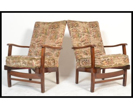 A pair of 1940's fireside armchairs in the manner of Heals of London. Each with mahogany frames having tapestry style cushion