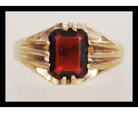 A hallmarked 9ct gold ring having a large faceted red stone with prong surrounds. Weighs 3.4 grams size U.