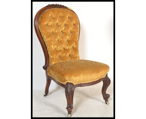A Victorian 19th century mahogany spoon back nursing chair of rococo form raised on scrolled legs with white ceramic castors 