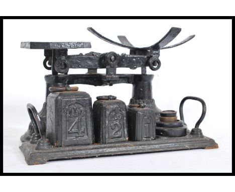 A vintage early 20th Century cast iron set of weighing scales complete with set of pillar weights. Painted ebonised finish wi
