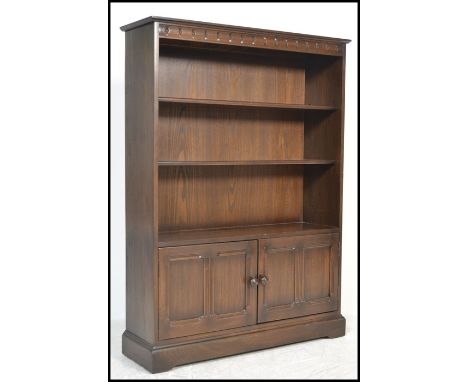 A 20th Century Ercol elm open bookcase, the bookcase having two adjustable shelves over to cupboard doors.&nbsp;Measures: 138