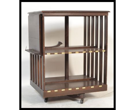 An Edwardian large mahogany revolving bookcase being raised on a four point swivel base with brown ceramic castors. Above an 