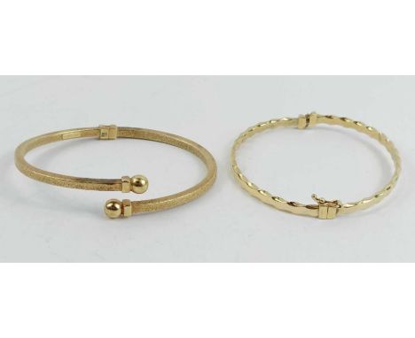 A hinged sprung bangle, stamped ‘375’, 5.7g gross; with an unmarked bangle, 3.5g gross  