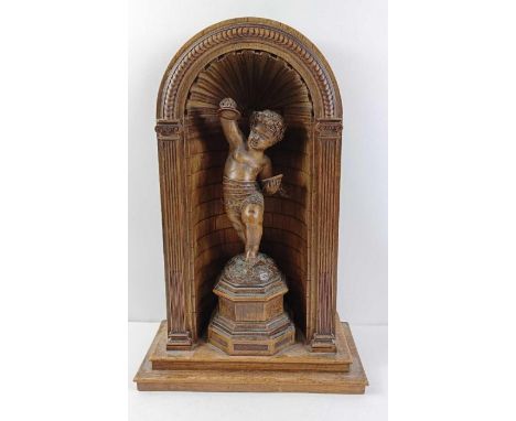 A 19th century hardwood carving of putti playing cymbals, standing in a arched frame and being raised on a pedestals, 38cm hi
